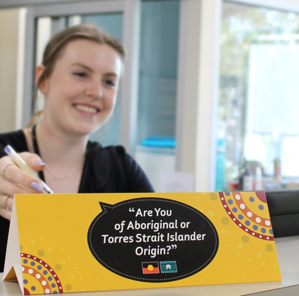 Woman pointing to sign that says are you of Aboriginal or Torres Strait Islander Origin