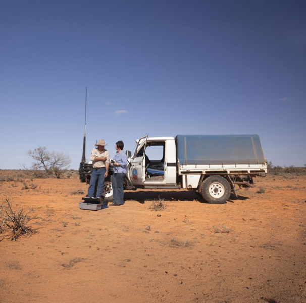 Woman doctor with male patient in the red soil outback next to a ute