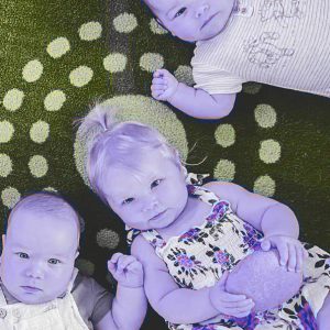 Three baby photograph lying down facing up to camera all colour with a purple tint