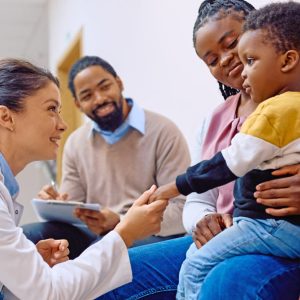 Doctor shaking hands with young child being held by mother