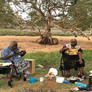 Senior aged women eating outside near a dry river bed