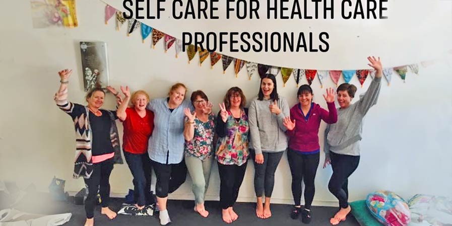 Group of people posing for photo - text self care for health professionals
