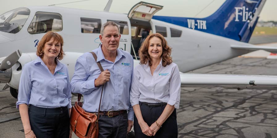 Three people in front of a small plane