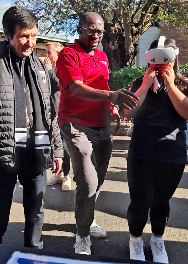 Image caption: A student explores rural practice through a virtual reality headset at the 2025 Western Sydney University Open Day in Parramatta, as the University Chancellor watches on. Photo credit: Bathurst Rural Clinical School