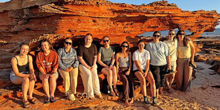 Group of people on a rocky beach at sunset
