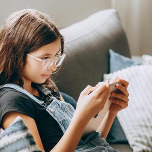 Young teen girl on an ipad sitting on a lounge