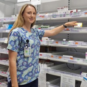 Pharmacist with medicine shelves