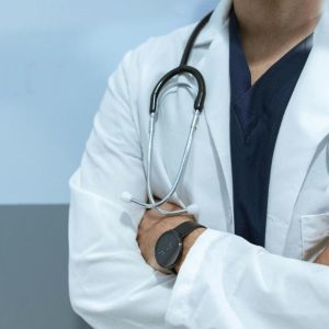 Doctor in white coat in front of Emergency sign