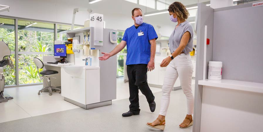 Two people walking through dental clinic with machines in the background
