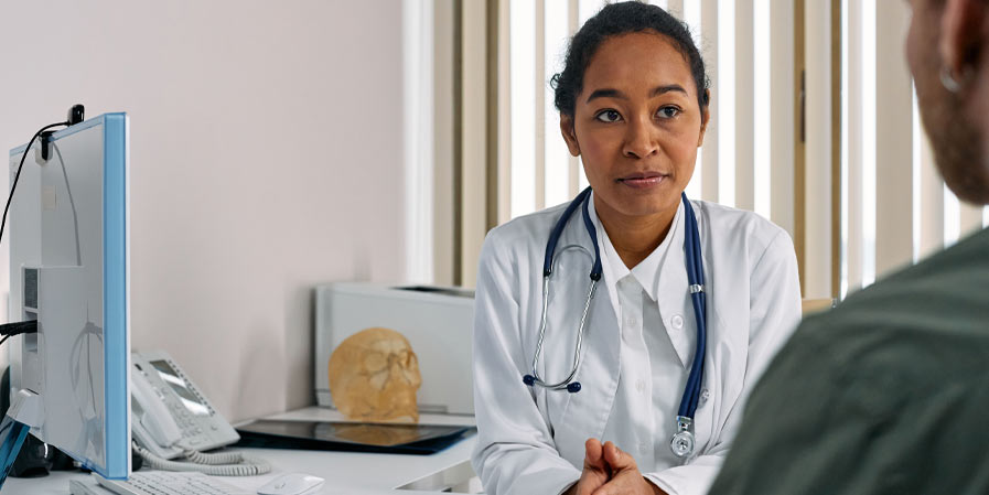 Doctor listening to patient with computer on desk