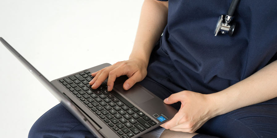 Nurse seated on floor using laptop