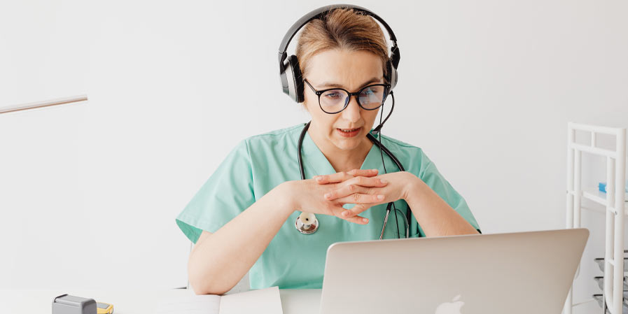 Doctor with headset on phone call with laptop in front