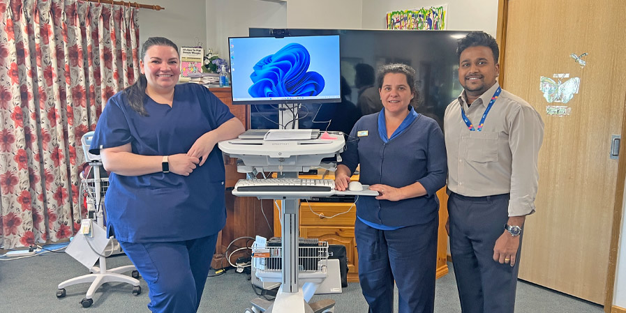 Registered Nurse Ashleigh Berry and Uralba Manager Katie White with MPHN Digital Health Project Officer Shivaram Ravulwar alongside the mobile telehealth equipment used for in‑room speech therapy consultations at Uralba Hostel in Gundagai.